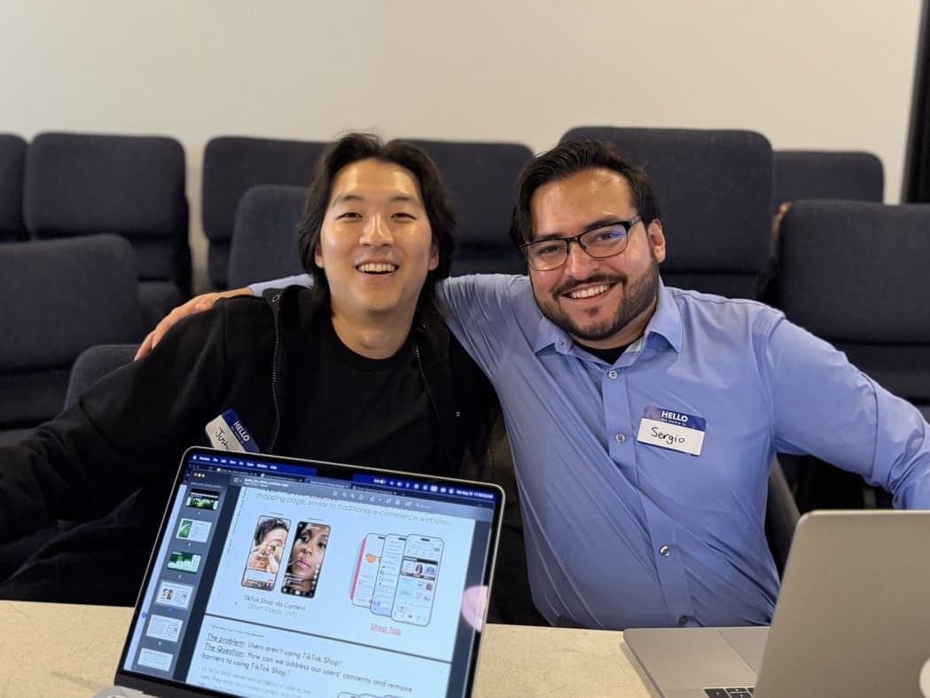 A mentor and mentee smiling together over a laptop