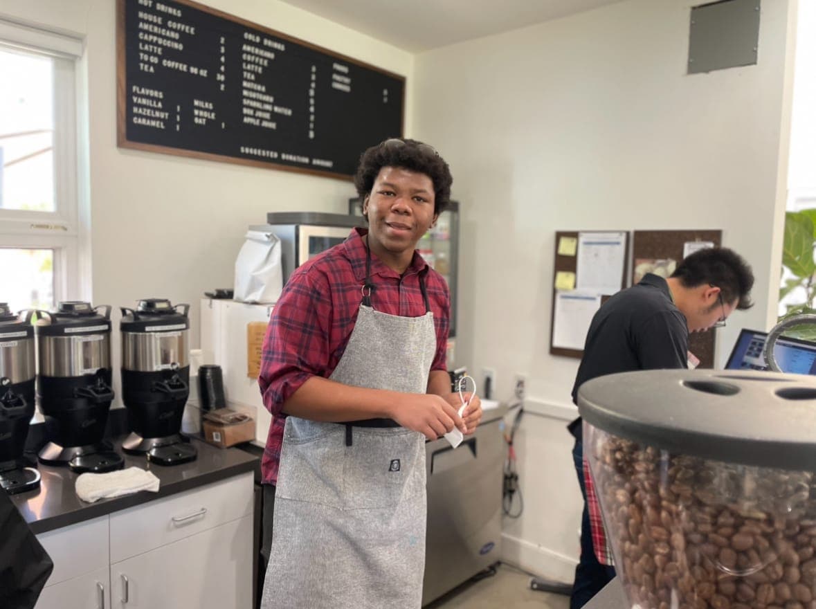 A young person working behind the counter at a cafe